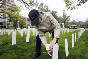 Karen Wolf of Bowling Green attaches the name of a service member to a tombstone. ‘I feel that the peace movement ended the war in Vietnam,'  she says. ‘I feel strongly that we can end these two wars.'