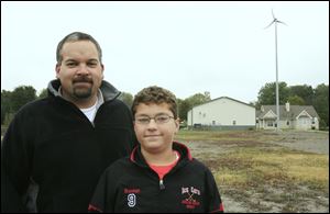 Sean Brennan and his son Nolan, 11, stand near their home in rural Bowling Green. Their devices save them money annually.
