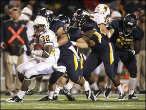 Wyoming running back Alvester Alexander is met by a wall of Rocket defenders in Saturday night game at the Glass Bowl. Toledo drops 3-2, while the Cowboys are 2-3.