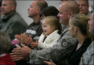 Tech Sgt. Shawn Doogs of Bloomdale, Ohio, with daughter Olivia on his lap, cheers during the ceremony. To his left is his wife, Tara; to his right are his parents, Ron and Jackie.