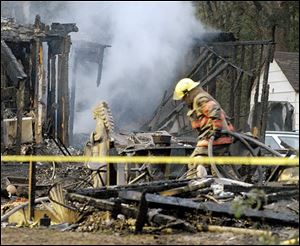 Firefighters work at the scene of a house fire that killed five people in Bartles, Ohio, on Monday. Seven other people were injured in the fire in rural southern Ohio. 