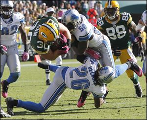 Packers fullback John Kuhn dives for an eight-yard gain against Detroit's Isaiah Ekejiuba and Louis Delmas. Kuhn finished the game with 39 yards rushing while the Lions' record fell to 0-4.