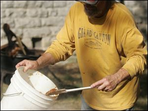 CTY butter11p  Gary Miller, of Neapolis, one of many volunteers who makes the festival happen, adding to the apple butter as it is cooked down. The Grand Rapids Applebutter Festival held on the streets of Grand Rapids, Ohio on October 10, 2010.  Jetta Fraser/The Blade