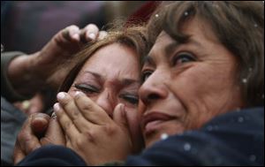 Roxana Gomez, left, daughter of miner Mario Gomez, is comforted by Maria Segovia, sister of trapped miner Dario Segovia, as they watch on TV Gomez's rescue Wednesday from the collapsed San Jose mine at the camp outside the mine near Copiapo, Chile.