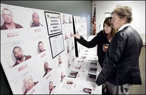 Lynn Jacquot, rear, director of the YWCA battered women's shelter, and Toledo Police Detective Mary Jo Jaggers, look at photos of fugitives caught by the Northern Ohio Violent Fugitive Task Force. 
