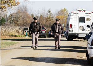 Cpl. Jeff Paterson, left, and Lt. Jeff Ewald of the Lenawee County Sheriff's Office walk by the home of Collin Fletcher on Terry Highway near Morenci, Mich.
