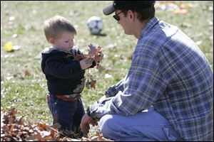 Brandon Tross, 1, finds leaves captivating as his father, Corey, watches. The Trosses live in Lambertville.