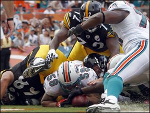 Miami linebacker Ikaika Alama-Francis (59) battles Pittsburgh quarterback Ben Roethlisberger after the QB fumbled the ball in the end zone. Officials ultimately gave the Steelers possession.