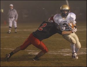Bedford's Tyler Hooven tackles Grosse Point South's Matthew Reno in Friday night's playoff game.