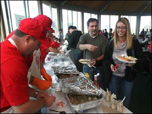 Joe Gunterman, left, owner of J&J Kielbasa, readies a piece for Russell and Theresa Pawlowski of Monclova Township at Bedford Hills Golf Club.