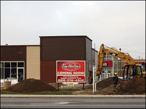 An excavator operator prepares ground for a parking lot at a Tim Hortons restaurant under construction at 1345 North Reynolds Rd. at the intersection of Dorr Street.