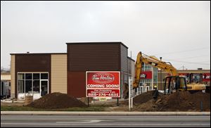 An excavator operator prepares ground for a parking lot at a Tim Hortons restaurant under construction at 1345 North Reynolds Rd. at the intersection of Dorr Street.