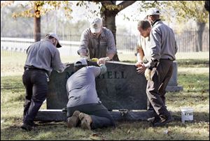 Bob Sobiniak, left, Tim Evans, Roger Wilhelm, Bryan Lorann, and Terry Rankin install a headstone at Toledo's Historic Woodlawn Cemetery. At least 50 markers were toppled there in March, 2009.