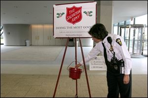 Toledo police Capt. Diana Ruiz-Krause contributes to the Salvation Army red kettle after the kickoff Thursday in the lobby of the Fifth Third Center in downtown Toledo. Bell ringers will be out in force this holiday season to collect $50,000 more than last year's $470,000.