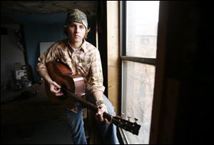 Michael Corwin strums a guitar in his downtown apartment.