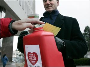 CTY newsboys04p 12/03/10  The Blade/Dave Zapotosky Michael Murnen of the Old Newsboys watches as a donor "buys" a copy of the group's "Goodfellow" charity newspaper outside One Government Center in Toledo, December 3, 2010. The group uses the donations from the sale of the papers to buy hats, gloves, coats, and shoes for needy children.