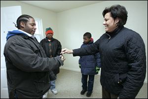 Adrian Hawkins, left, gets the keys to a newly renovated Lucas Metropolitan Housing Authority home from property manager DeAnna Ellis. In the background are his sons, Adrian, Jr., 14, and Ben, 10.