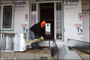 A contractor carries heating ducts to a house under construction in Gretna, Neb. While the overall economic recovery looks durable, the housing index still indicates consumer pessimism.
