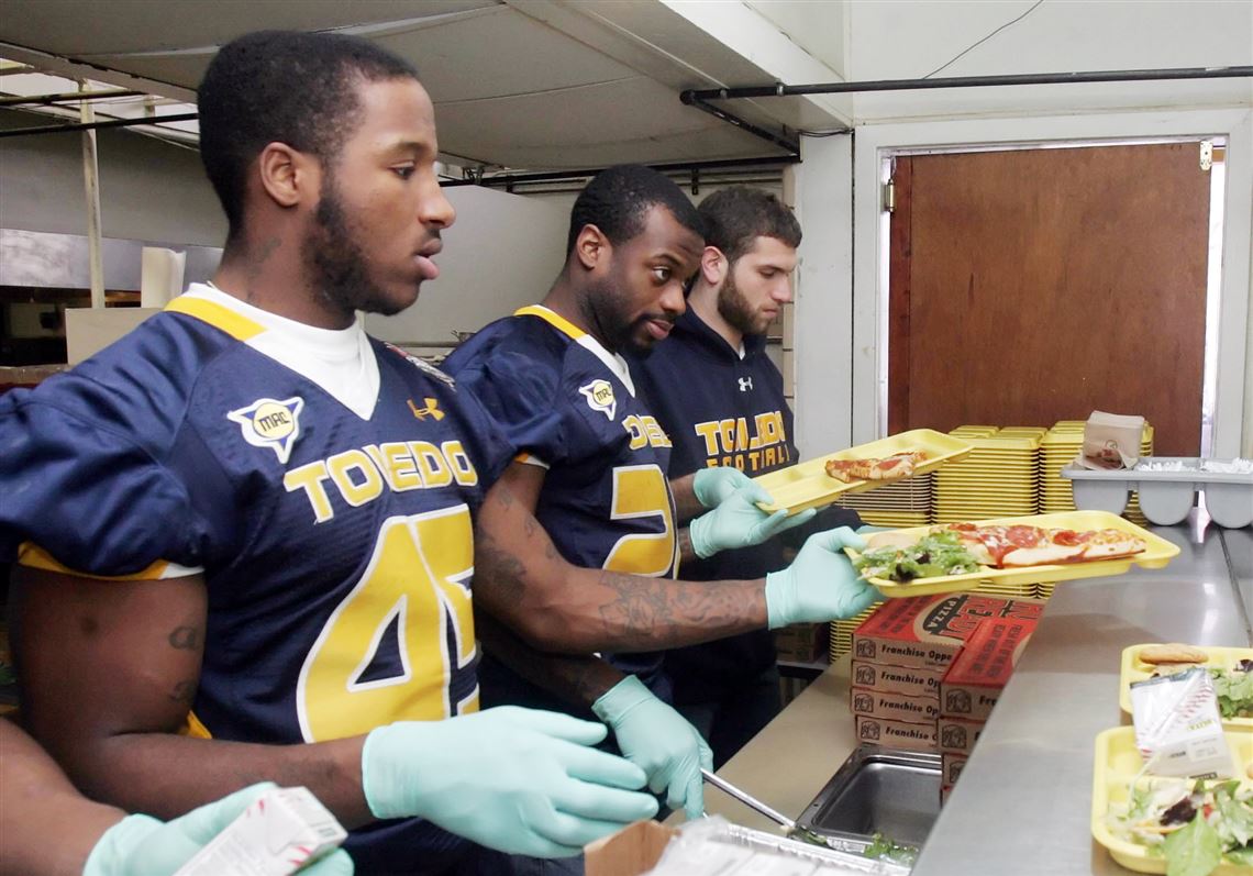 CTY pizza18p The Blade/Lori King 12/17/2010 University of Toledo football players from left: Isaiah Ballard, Adonis Thomas and Colin McHugh serve Little Caesars pizza to the needy at the Cherry Street Mission kitchen on Madison Ave. in Toledo, Ohio. S7 18s7pizza 3.6