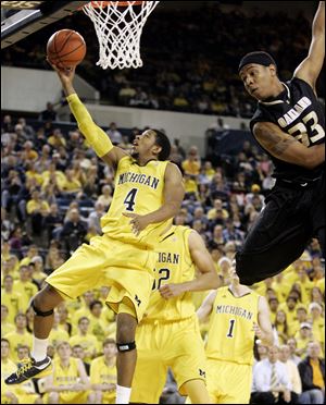 Michigan's Darius Morris goes to the basket past Oakland's Ryan Bass. Morris had 18 points for the Wolverines.