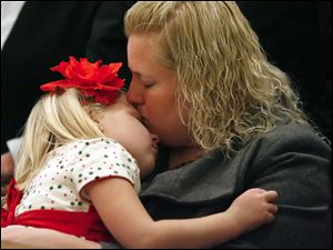 Slug: CTY XMASPIC24 01  The Blade/Jeremy Wadsworth  Caption: Amy Firsdon of Oregon, Ohio, comforts her daughter Samantha, 6, Friday, 12/24/10, during the Christmas Eve Mass at the Rosary Cathedral in Toledo, Ohio. Bishop Leonard Blair is the celebrant.