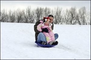 SLUG:  ROV christmassled                          12/25/2010 The Blade/Amy E. Voigt                           Toledo, Ohio   CAPTION:  Chris Kelsey, from Toledo, and his daughter Harmony Kelsey, 2, zip down the hill on the sled Kelsey got for Christmas in Highland Park on December 25, 2010.