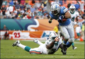Detroit's DeAndre Levy manages to escape the grasp of Dolphins defender John Kerry last Sunday during the Lions' win in Miami.