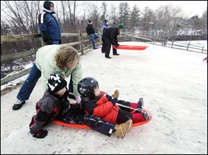 ROV sledding29p  The Blade/Lori King  12/29/2010  Melissa Salazar pushes her sons, Sammy, 7, and Zachary, 4, down the new sledding hill at Side Cut Metropark in Maumee, Ohio. The family moved to Perrysburg from Florida this summer. This is the 2nd time the boys have ever sledded (their first time was yesterday on this hill).