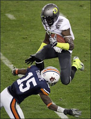 Oregon's Lache Seastrunk leaps over Auburn's Neiko Thorpe in the first half of Monday night's BCS national championship game.
