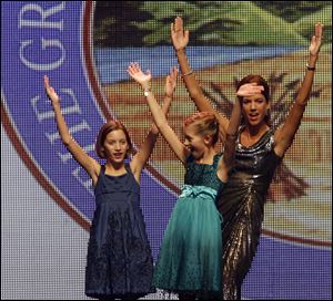 Kasich twins Reese, left, and Emma join their mom, Karen, for a spirited O-H-I-O cheer as the Ohio State band plays the university's fight song near the end of Monday night's inaugural gala in Columbus.