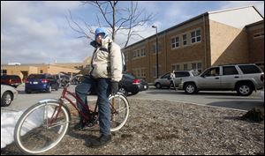 Gregory Reichert II, a junior, waits for automobile traffic to clear before heading home on his bicycle. 
