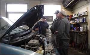 Jeff Stang, left, and Michael Canning, right, talk with customer Jeremy Miller about repairs to his van.