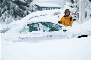Howard Slovin of Hockessin, Del., digs his car out of the snow in his driveway.