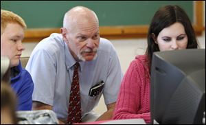 Teacher Jim Miller confers with Whiteford students Zack Niederkohr and Sarah Bowes on their stock picks.
