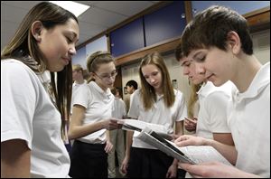 At St. Joan of Arc, Whitney Stolnicki, left, Miranda Robertson, Lauren Boehler, Corinne Tipping (hidden), Camden Buescher, and John Toth study The Blade's daily stock listings.