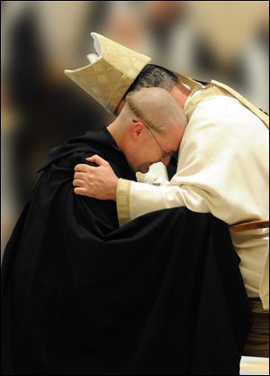 Newly professed monk Brother Francis de Sales Wagner is embraced by Archabbot Justin DuVall.