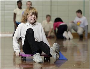 Delani Fuller, a Walbridge Elementary student, rolls in a relay race that requires problem solving with geometric shapes and joining in cooperative learning as well as aerobic physical activity. 