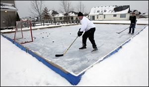 Bob Felser, foreground, plays hockey on his homemade backyard skating rink in Sylvania Township. 