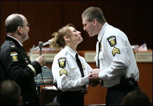 Newly promoted Lt. Kelli Russell receives a kiss and her new lieutenant's badge from her husband, Sgt. Corey Russell, during the Toledo police promotions ceremony while Chief Mike Navarre, left, watches.