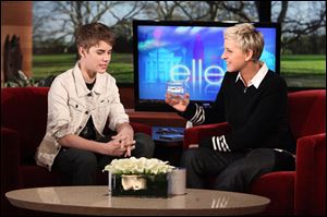Ellen DeGeneres, right, listens to singer Justin Bieber as she holds a box containing strands of his hair.