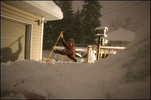 Mary Jane Holloway of South Toledo sweeps the snow off her car early Friday morning before heading to work. 