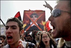 Egyptian protesters chant slogans as they hold an anti-poster of Libyan Leader Moammar Kaddafi during a Friday demonstration in Tahrir Square in Cairo, Egypt.