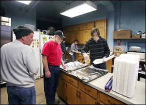 From left, Bill Stebelton, Knute Huber, and Javier Sevilla, 16, prepare a take-out meal at Salem Lutheran Church on North Huron. The twice-monthly free pancake breakfast feeds the needy in the neighborhood.