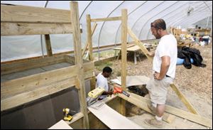 Site supervisor Brian Ellis, right, watches as Willy Share builds one of two large fish tanks for a tilapia farm at Oneida Greenhouse last August.