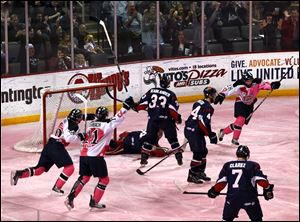 Toledo players celebrate a goal by Mike Hedden on the pink ice while playing the Kalamazoo K-Wings.