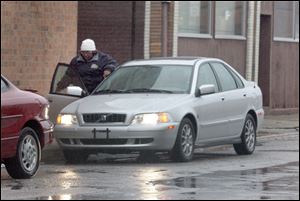A Lucas County sheriff's employee leaving work enters the passenger door of a Volvo parked on Canton Street in downtown Toledo. She refused to talk about her car ownership.