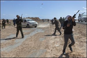 Opposition fighters fire at an approaching helicopter moments before it fired back, as they are pushed out of Bin Jawad and back towards Ras Lanuf, in eastern Libya, Sunday.