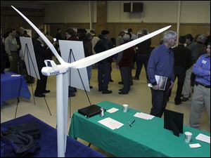 A model of a wind turbine is displayed as residents chat with members from the Blissfield Wind Energy project team during an open house. In the foreground are John Richey, left, and John Bulloch.