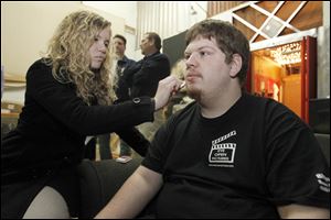 Paige Ramsey, left, puts make-up on crew leader Eric Badik.