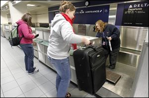 tElizabeth Romuald, left, checks in for Delta's last flight from Toledo Express while her sister Anna, who was seeing her off to Minneapolis, lifts her bag onto the scale. 